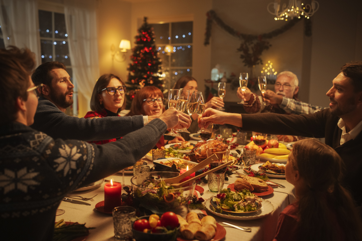 Family clinking wine glasses at a Christmas dinner table during a festive holiday celebration.